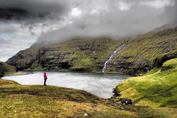 Bucht im Nebel mit Mann in roter Jacke auf den Färöer