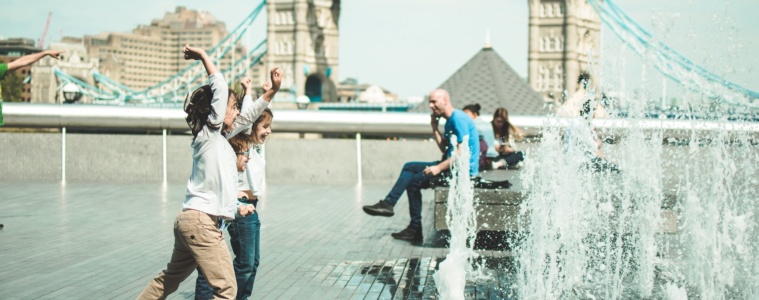 Kinder in London spielen an öffentlichem Wasserstrahl vor der Tower Bridge