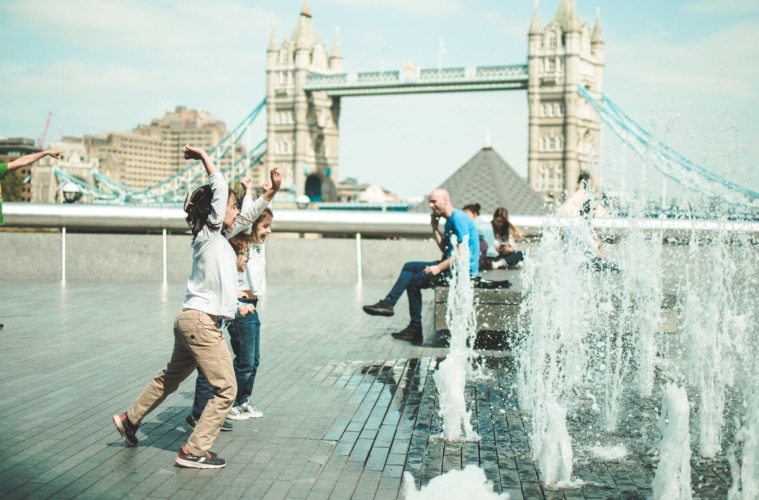 Kinder in London spielen an öffentlichem Wasserstrahl vor der Tower Bridge