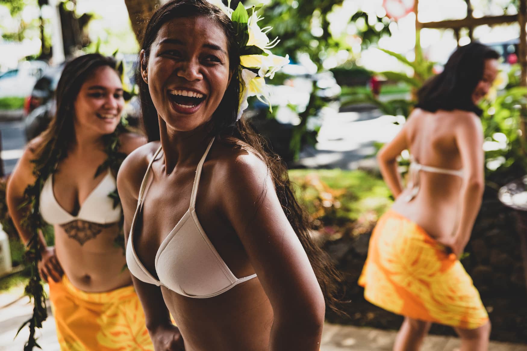 Frauen aus Französisch-Polynesien tanzen in bunten Wickelröcken und lächeln