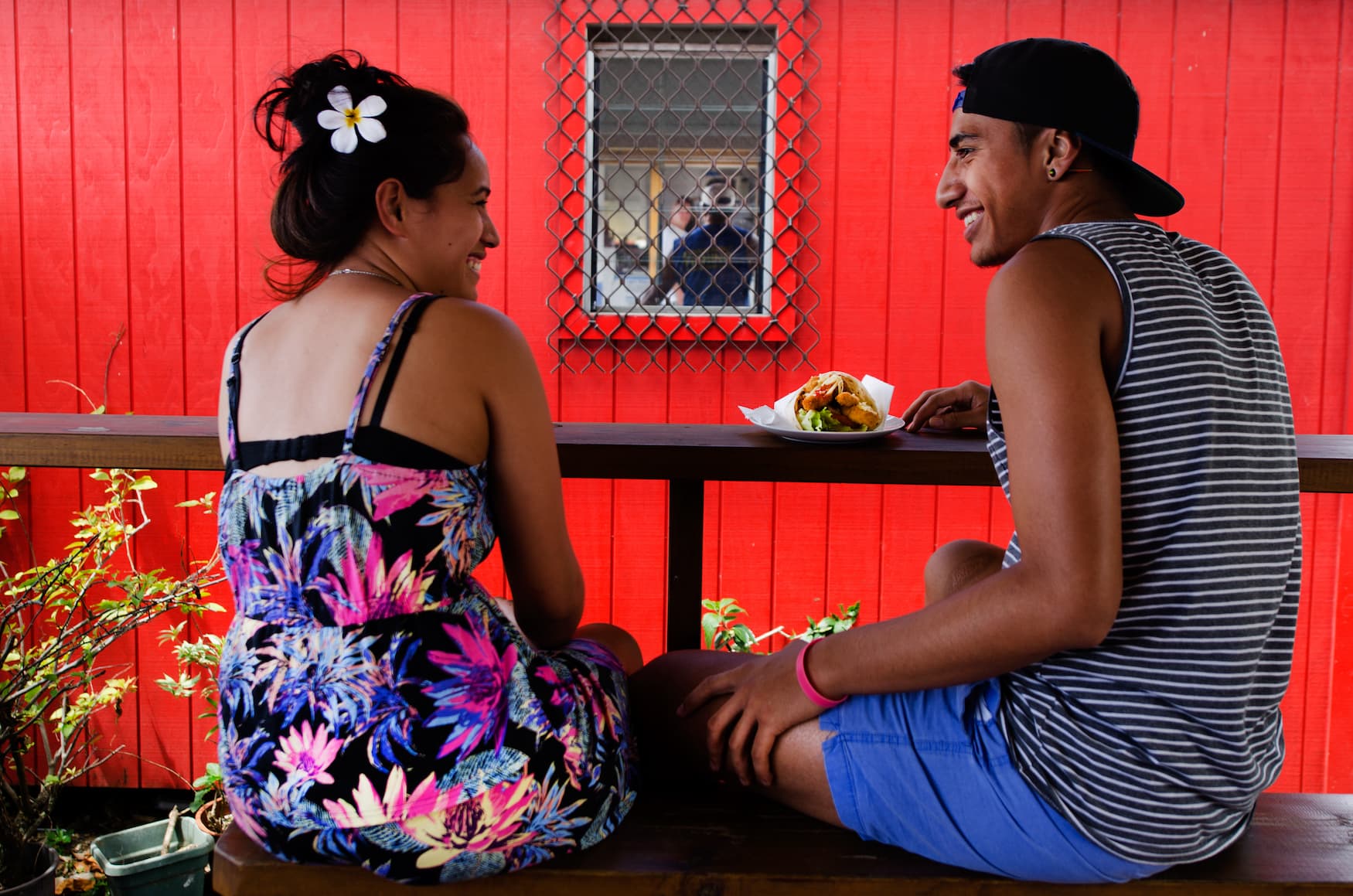 Junges Pärchen auf den Cook-Inseln sitzt in einem Restaurant und lächelt sich an