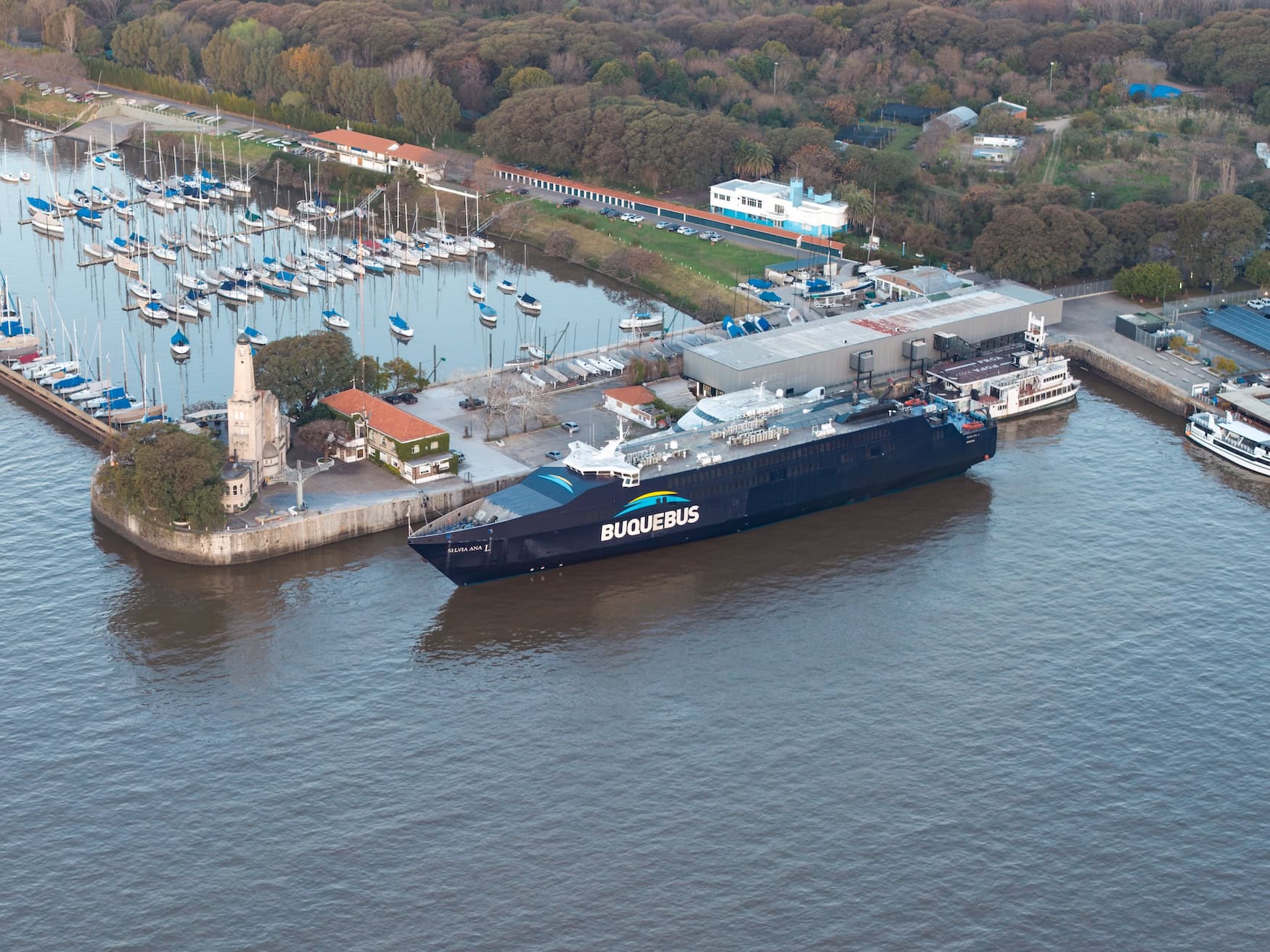 Kielwasser einer Fähre auf dem Río de la Plata, im Hafen dahinter liegt eine Buquebus-Fähre.