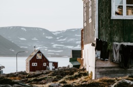 Zwei Holzhütten stehen vor verschneiter Landschaft auf Grönland