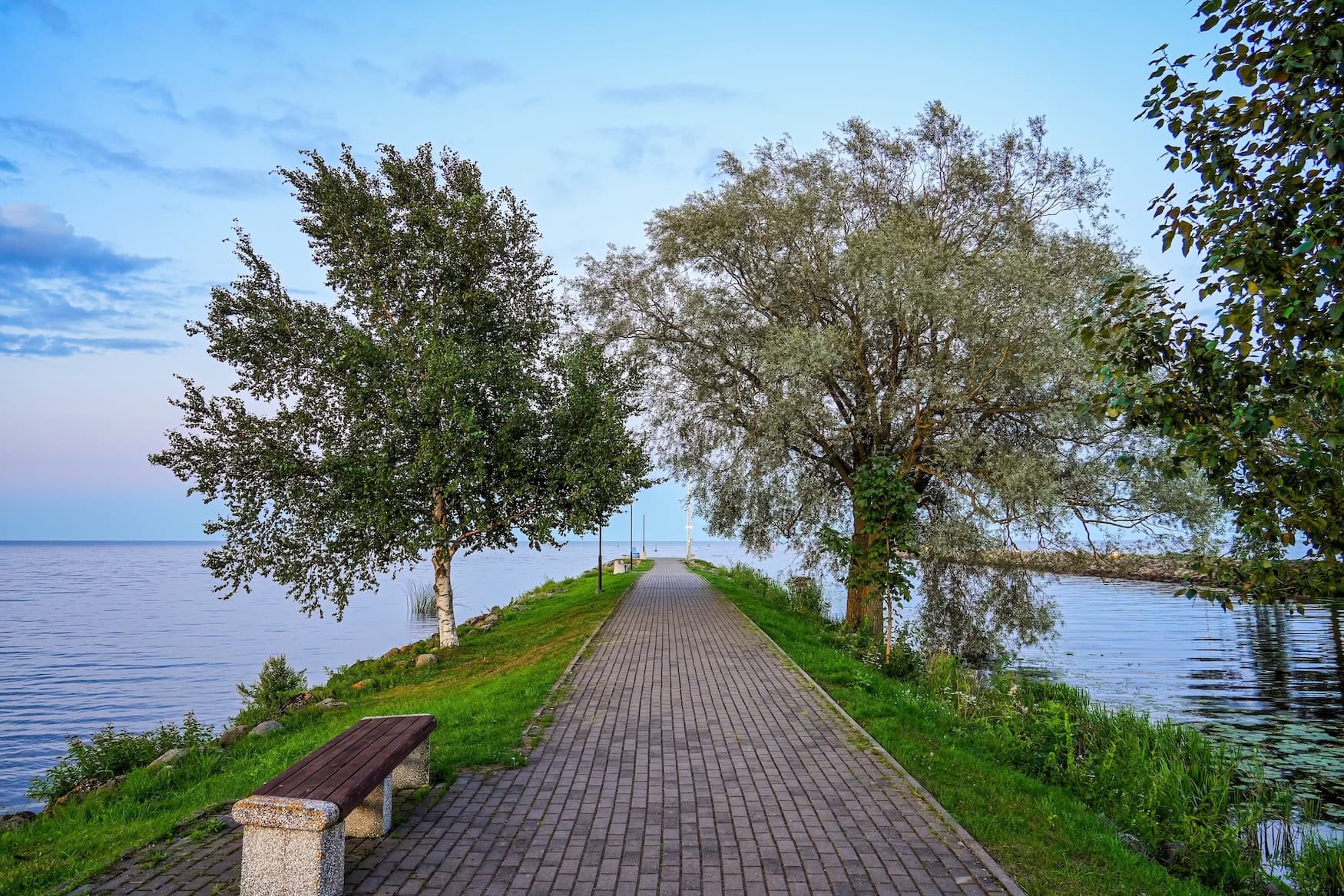 Spazierweg auf einer Mole mit Bäumen am Ufer des Peipussees in Estland.
