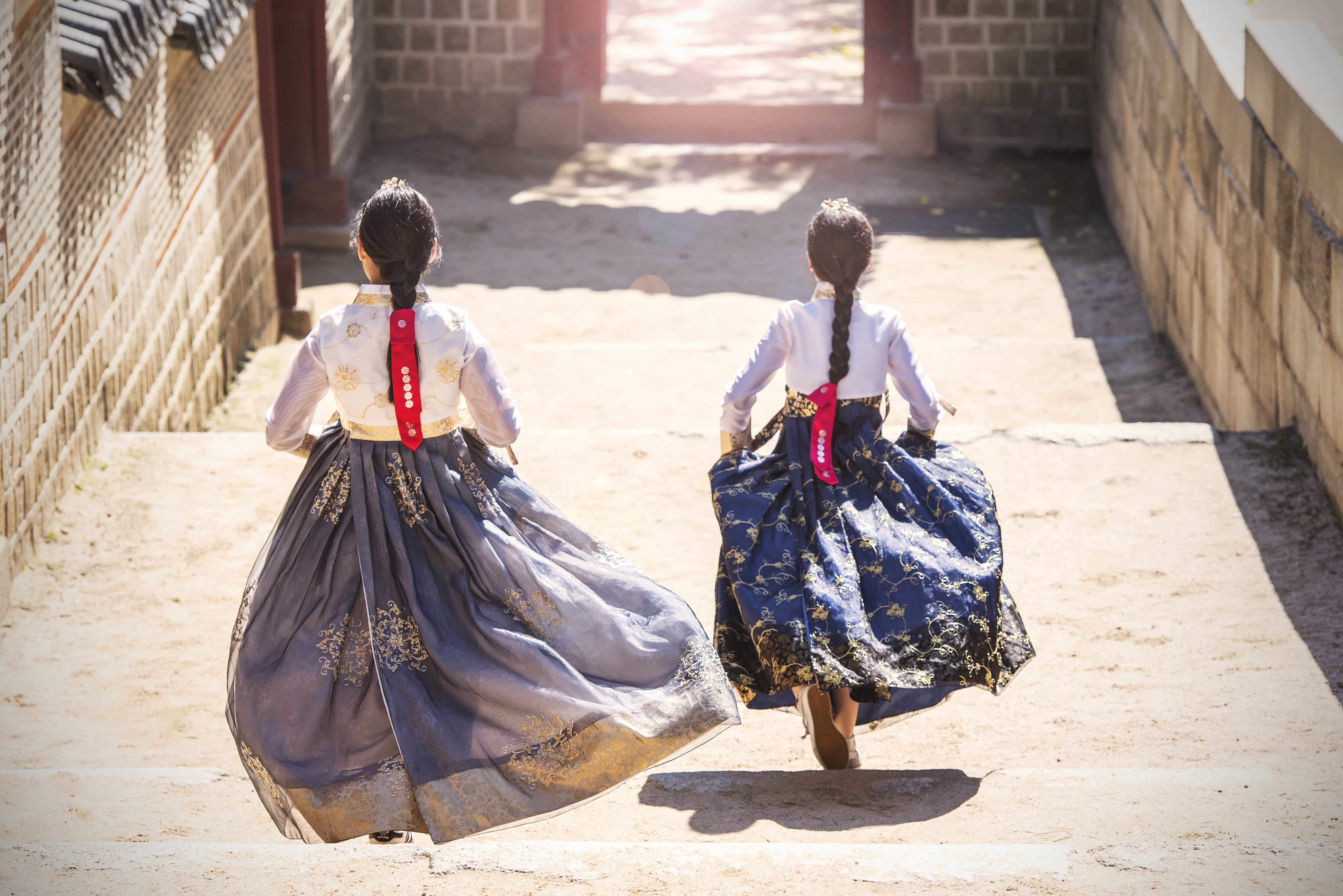 Mädchen in traditioneller südkoreanischer Kleidung laufen Treppen hinab