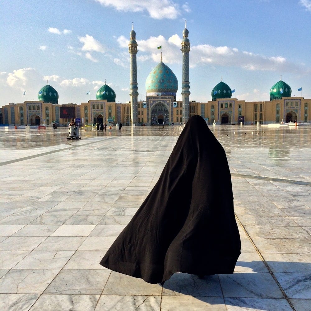 Verschleierte Frau auf einem großen Platz vor einer Moschee