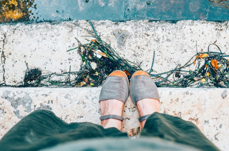 Frau mit Espadrilles steht auf Stufe am Hafen