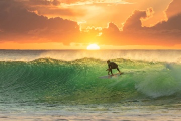 Surfer reitet die perfekte Welle im Sonnenuntergang.