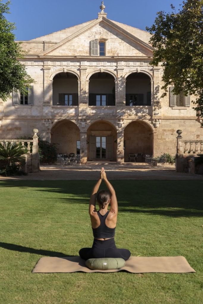 Frau macht draußen Yoga auf einer Matte im Vestige Son Vell auf Menorca