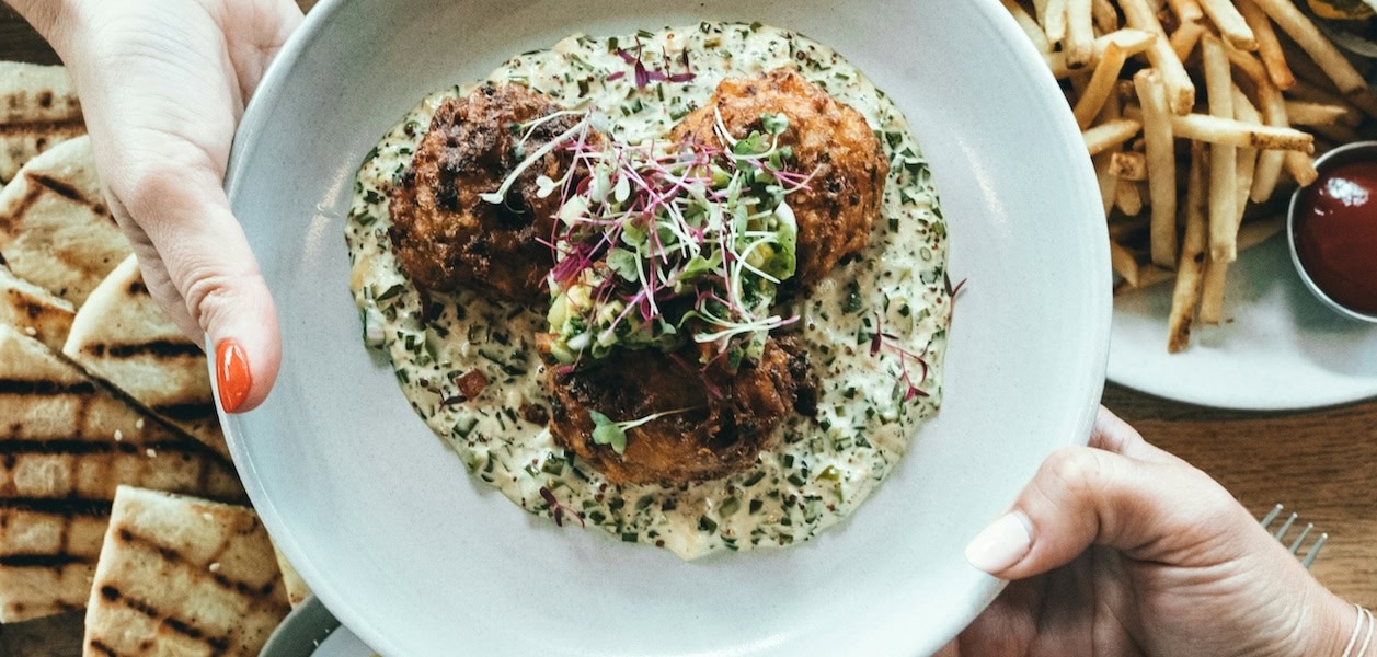 Ein Teller mit Essen wird über den Tisch gereicht.