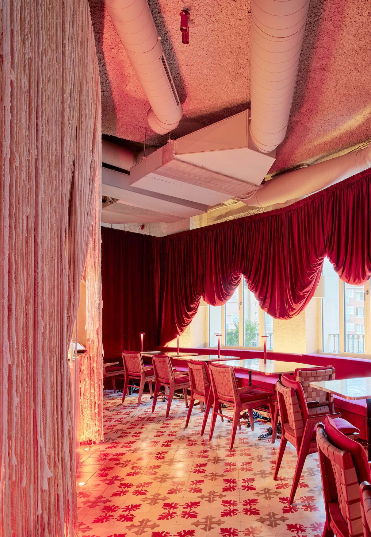 Leuchtend roter Gang im Terreno Barrio Hotel mit dem Wandmotto In local we trust und Blick zur Rezeptions-Bar