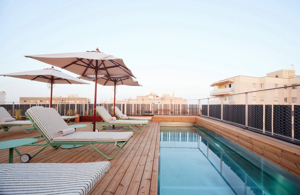 Dachpool des Terreno Barrio Hotel auf hellem Holzdeck mit Liegen und Blick über die Dächer von El Terreno