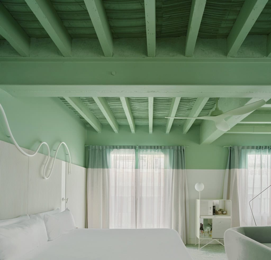 Suite Joan Miró im Terreno Barrio Hotel mit geschwungener Neonlinie über dem Bett und salbeigrünem Wandpaneel