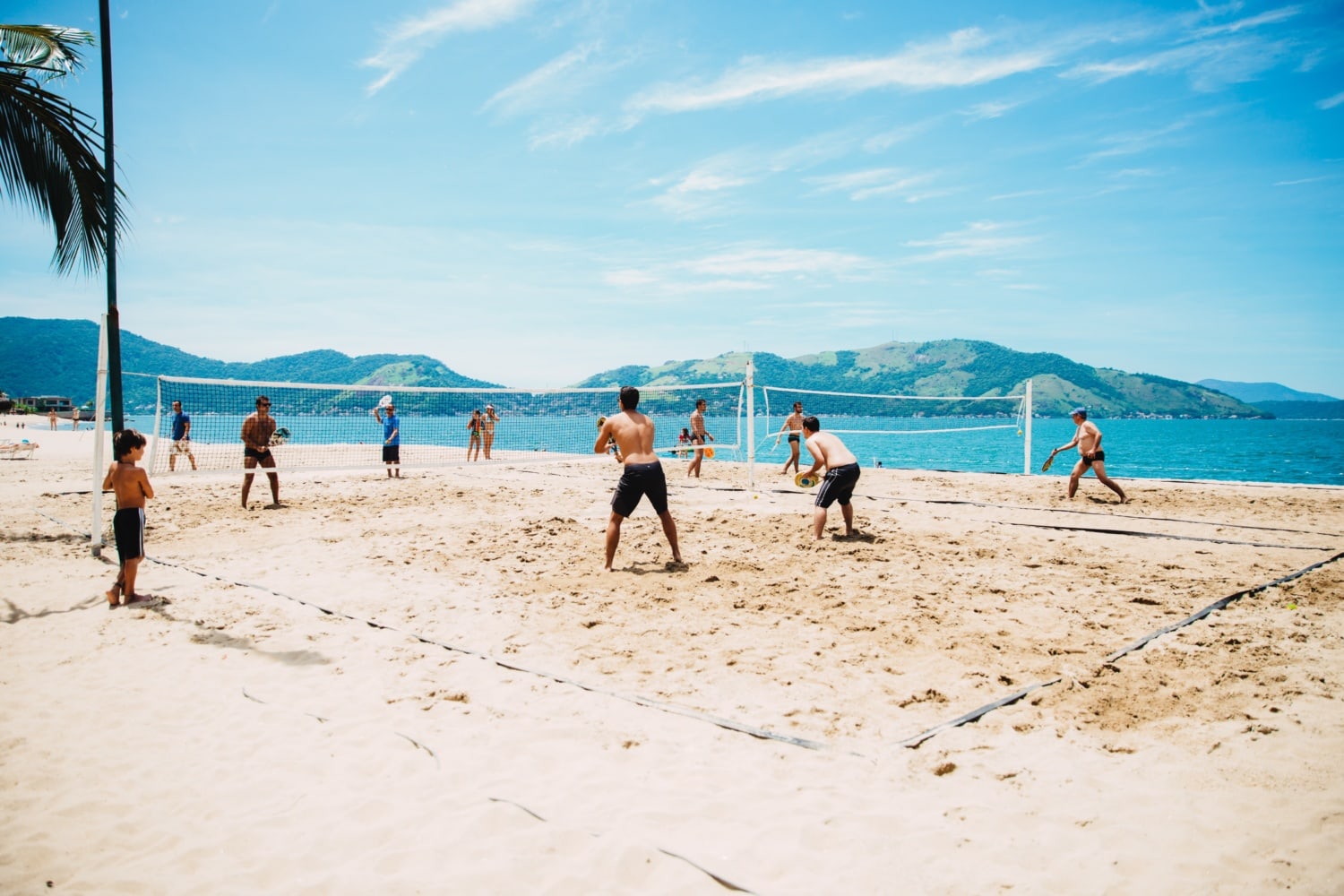 Gruppe von Männern spielt Volleyball am Strand