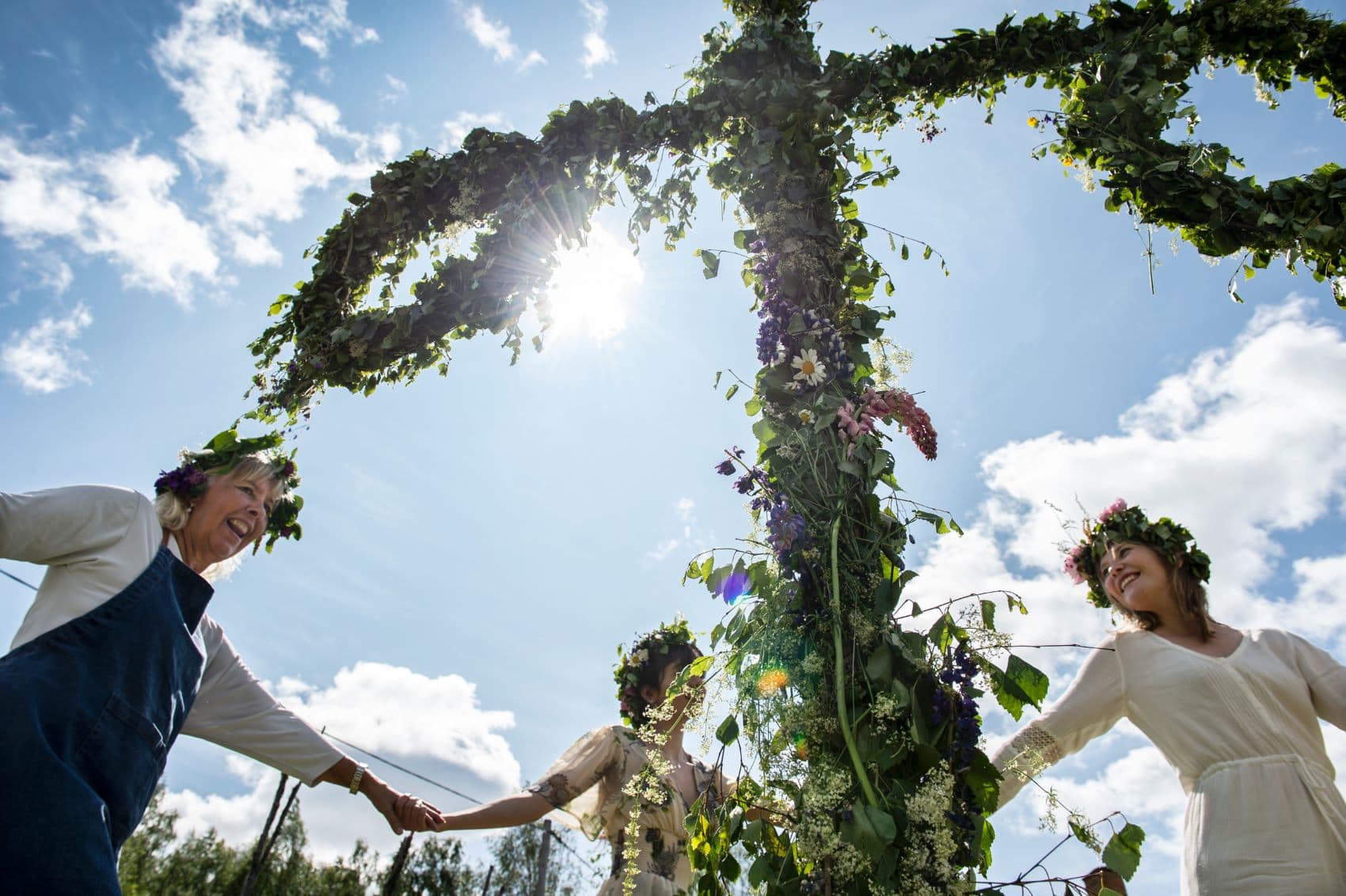 Frauen tanzen während am Mittsommerfest in Schweden um einen Baum 