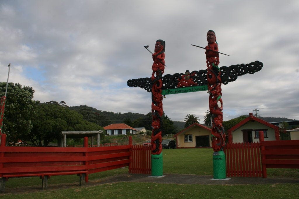 Am Ostkap in Neuseeland zieren Maori-Figuren den Eingang zu einem Versammlungshaus.