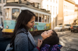 Mutter und Tochter lächeln sich an in Straße in Lissabon, Portugal