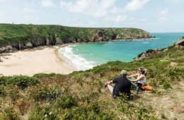 Mann und Frau sitzen auf einem Hügel in der Plemont Bay auf der Insel Jersey
