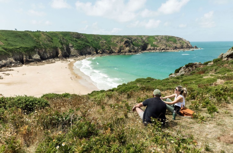 Mann und Frau sitzen auf einem Hügel in der Plemont Bay auf der Insel Jersey