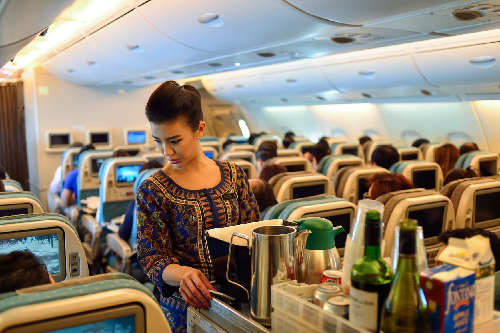 Stewardess von Singapore Airlines beim Ausschenken von Speisen und Getränken