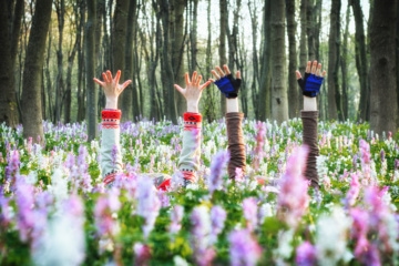 Mädchenhände ragen aus Blumenwiese hervor