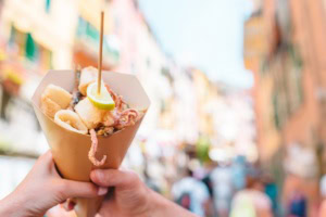 Streetfood in Italien – gegrillte Kalamari, Schrimps und Gemüse in einer Tüte.