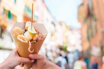 Streetfood in Italien – gegrillte Kalamari, Schrimps und Gemüse in einer Tüte.