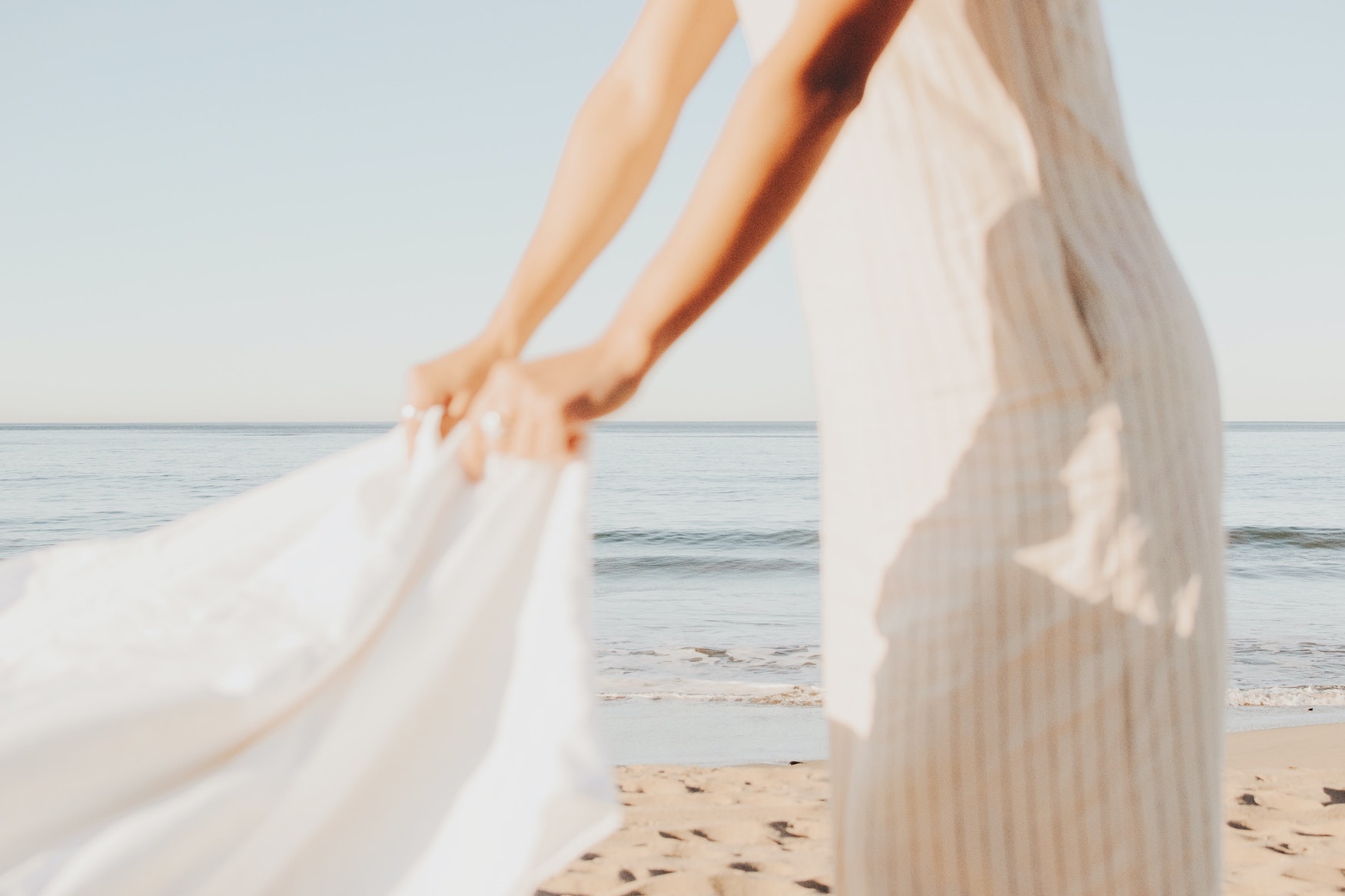Frau trägt helle Leinenkleidung am Strand gegen die Hitze