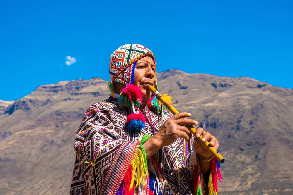 Einheimischer in Cusco in Peru mit traditioneller Kleidung und Flöte