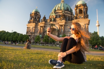 Junge Frau macht Selfie auf Wiese in Berlin