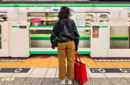 Eine Frau steht an einem Bahnsteig in Tokio.