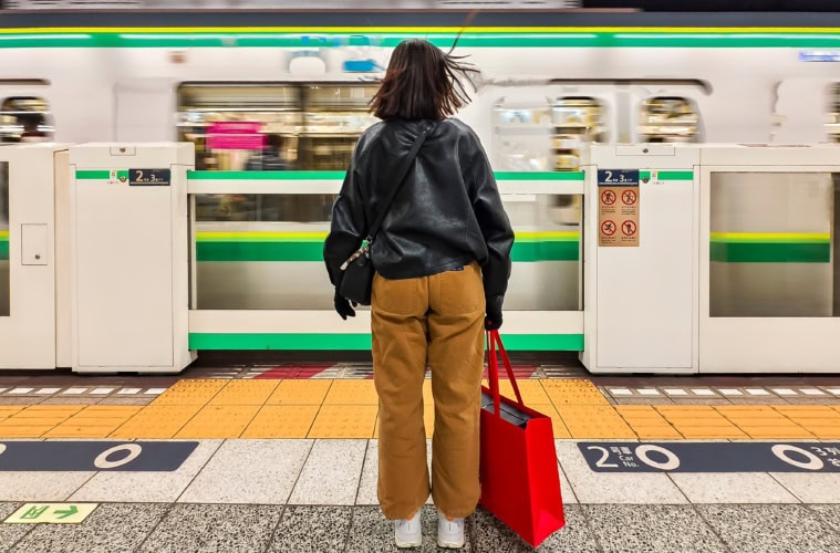 Eine Frau steht an einem Bahnsteig in Tokio.
