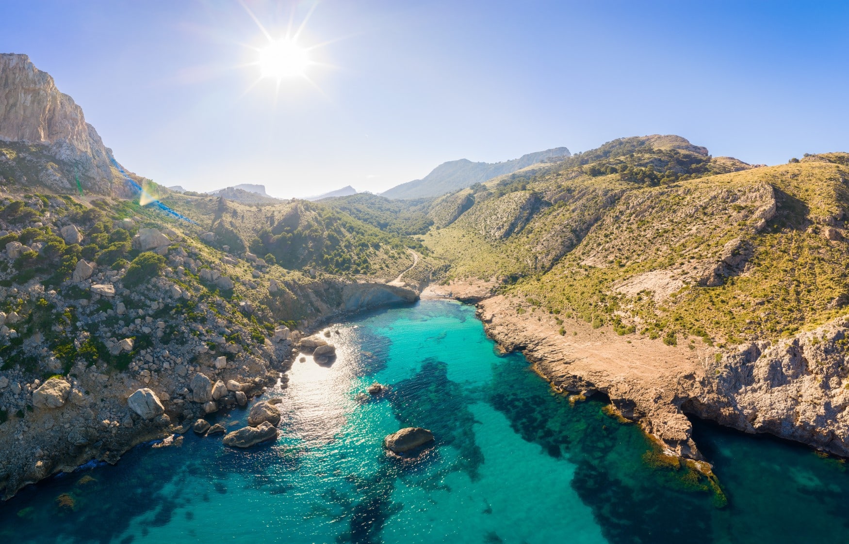Drohnenaufnahme des Strands Playa Formentor auf Mallorca, links und rechts gehen grüne Hügel in die Höhe.