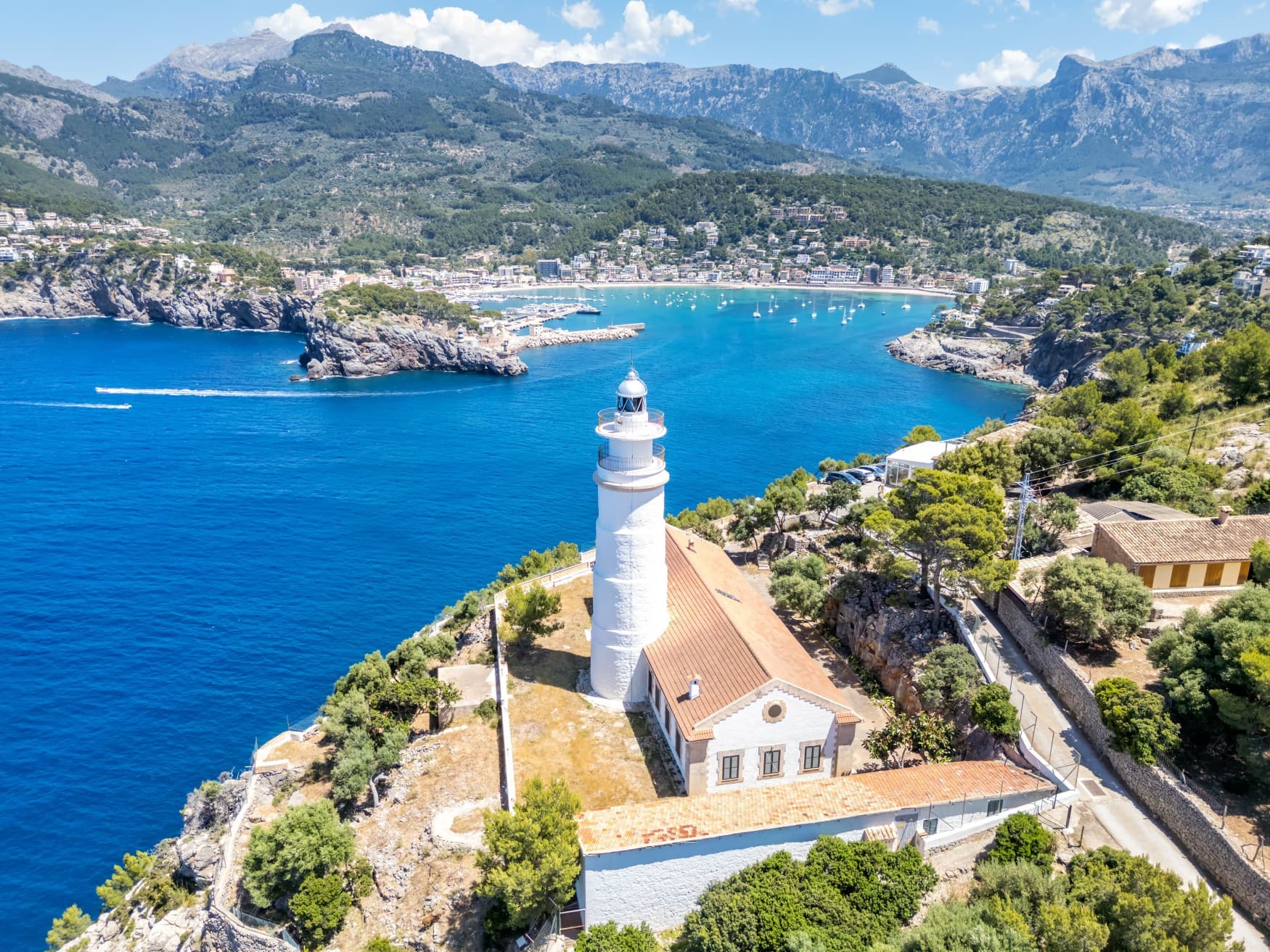 Luftaufnahme eines weißen Leuchtturms auf der Klippe über dem Port de Sóller auf Mallorca.
