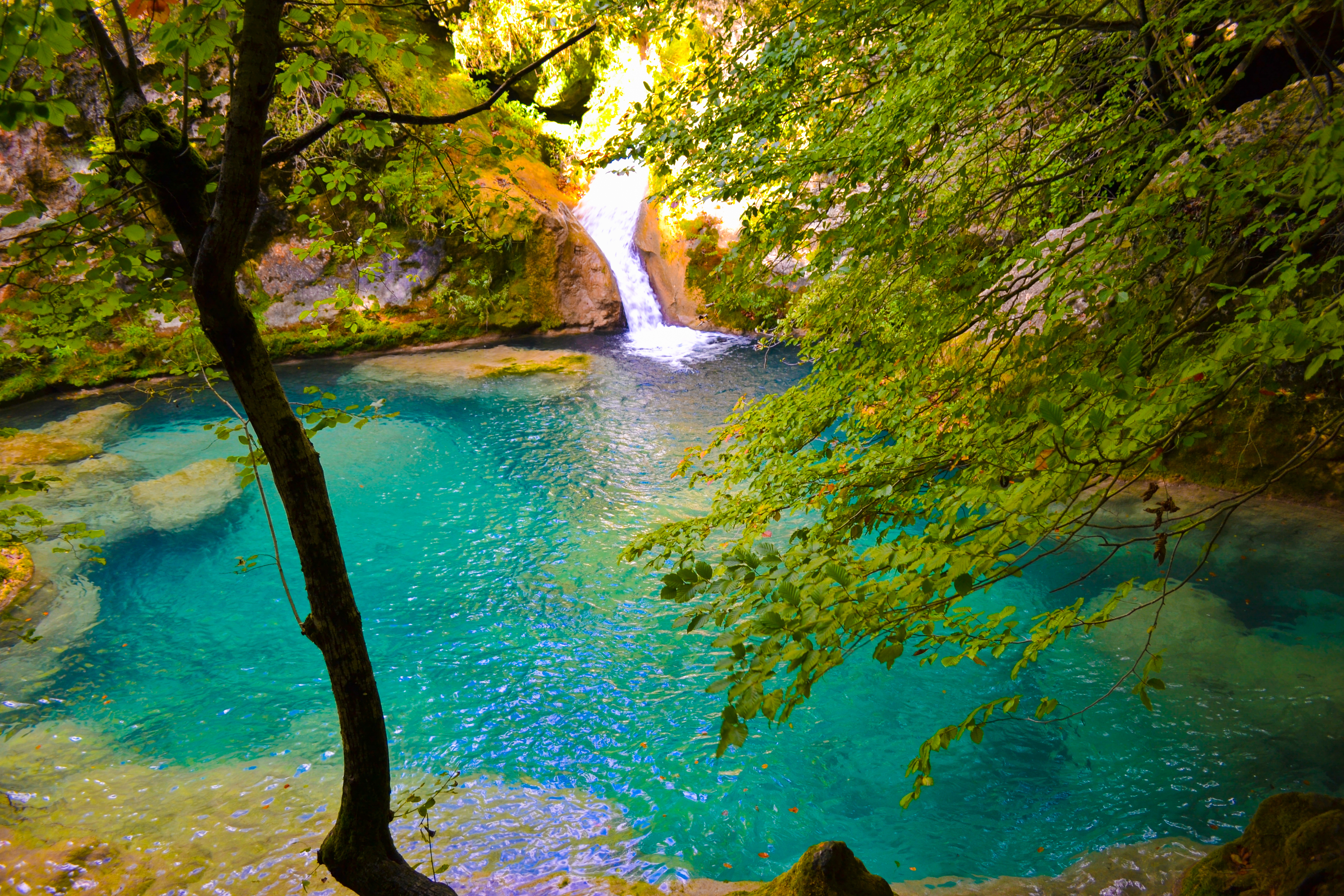 Wasserfal mit kleinem Bergsee mit türkisfarbenem Wasser mitten im Grün des Waldes