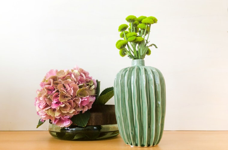 zwei verschiedene Vasen, eine mit Holz, eine aus Keramik mit schönen blumen