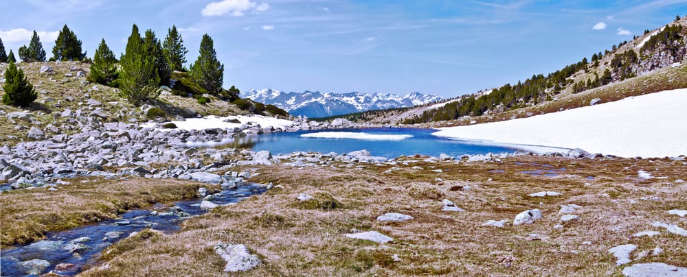 Bergsee mit Resten von Schnee und Panorama 