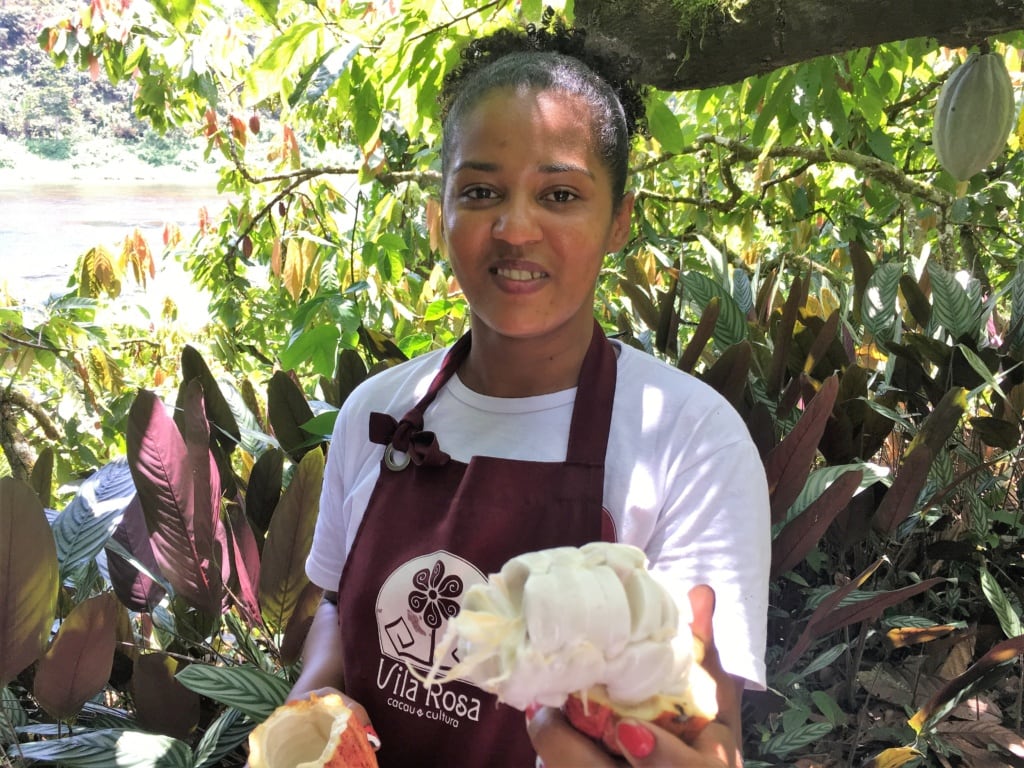Mitarbeiterin der Vila Rosa in Bahia hält in ihrer Hand das Fruchtfleisch der Kakaobohne