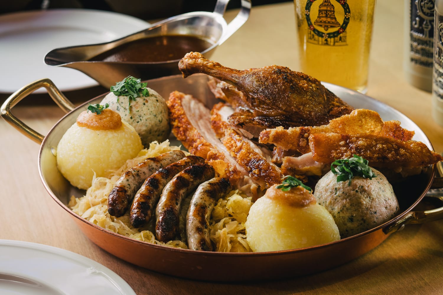 Teller mit Nürnburger Bratwürste, Sauerkraut und Klößen in uriger Atmosphäre.
