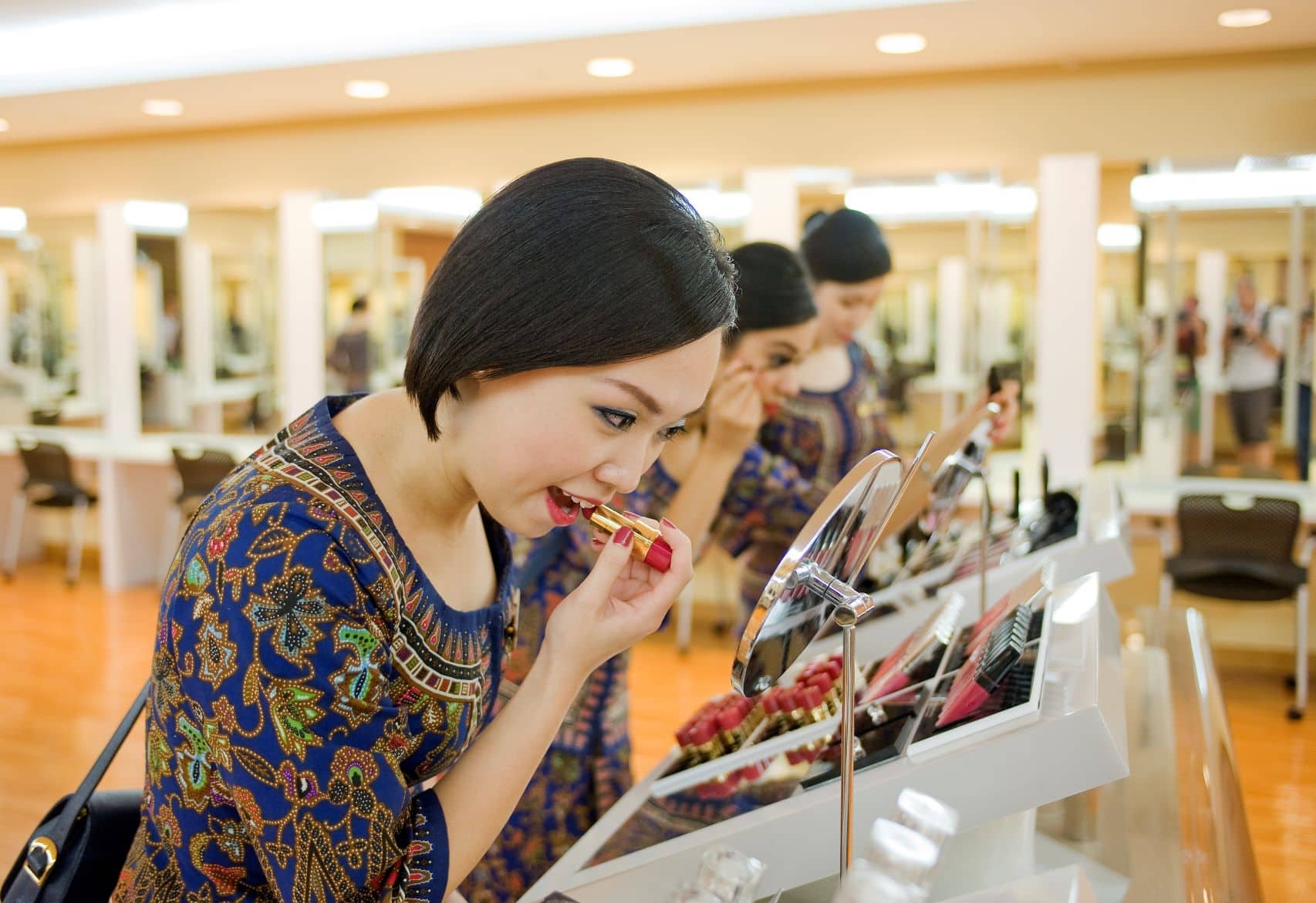 Singapore Girl mit Lippenstift vor Spiegel
