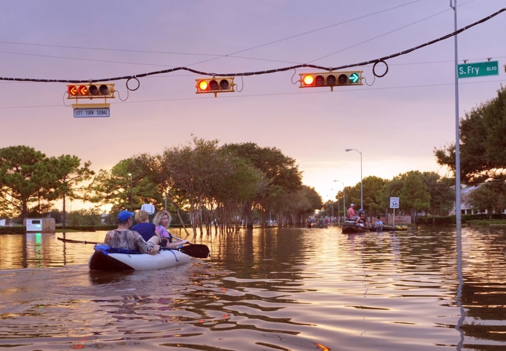Menschen im Schlauchboot auf überfluteter Straße