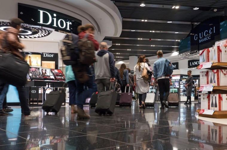 Passagiere laufen am Dior-Shop im Flughafen London vorbei