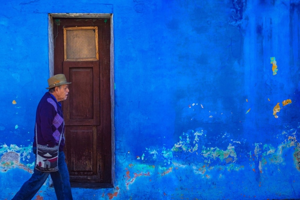 Älterer Mann geht in Antigua (Guatemala) an einer blauen Hauswand vorbei