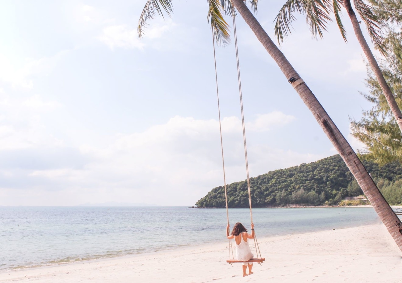 Frau auf Schaukel an Palme am Strand in Thailand