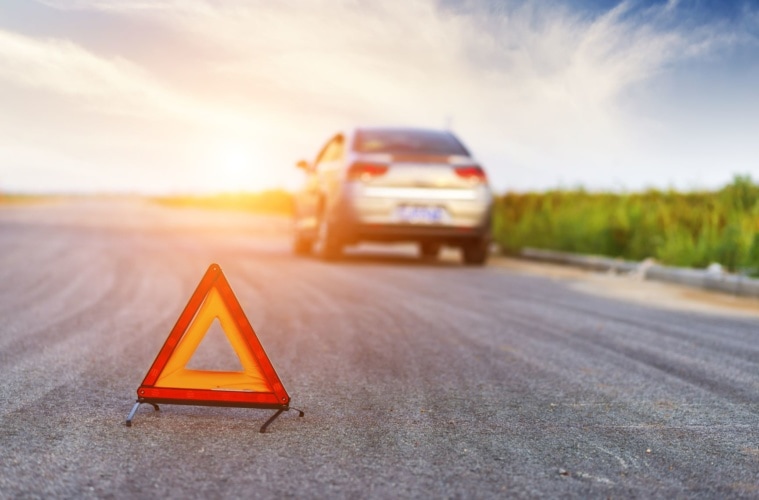 Warndreick auf Straße, im Hintergrund Auto