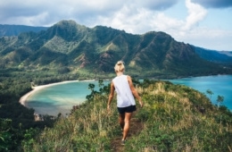 Blonde Wanderin blickt bei einer klassischen Hawaii-Wanderung über den Ozean.