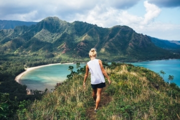 Blonde Wanderin blickt bei einer klassischen Hawaii-Wanderung über den Ozean.