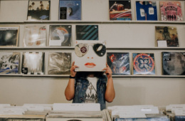 Frau hält sich im Schallplatten-Laden Cover vors Gesicht