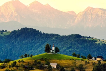 Urlaub in Slowenien: Kirche auf Hügel, im Hintergrund Berge