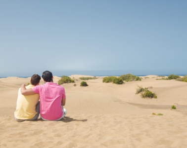 Schwules Paar sitzt in den Dünen auf Gran Canaria